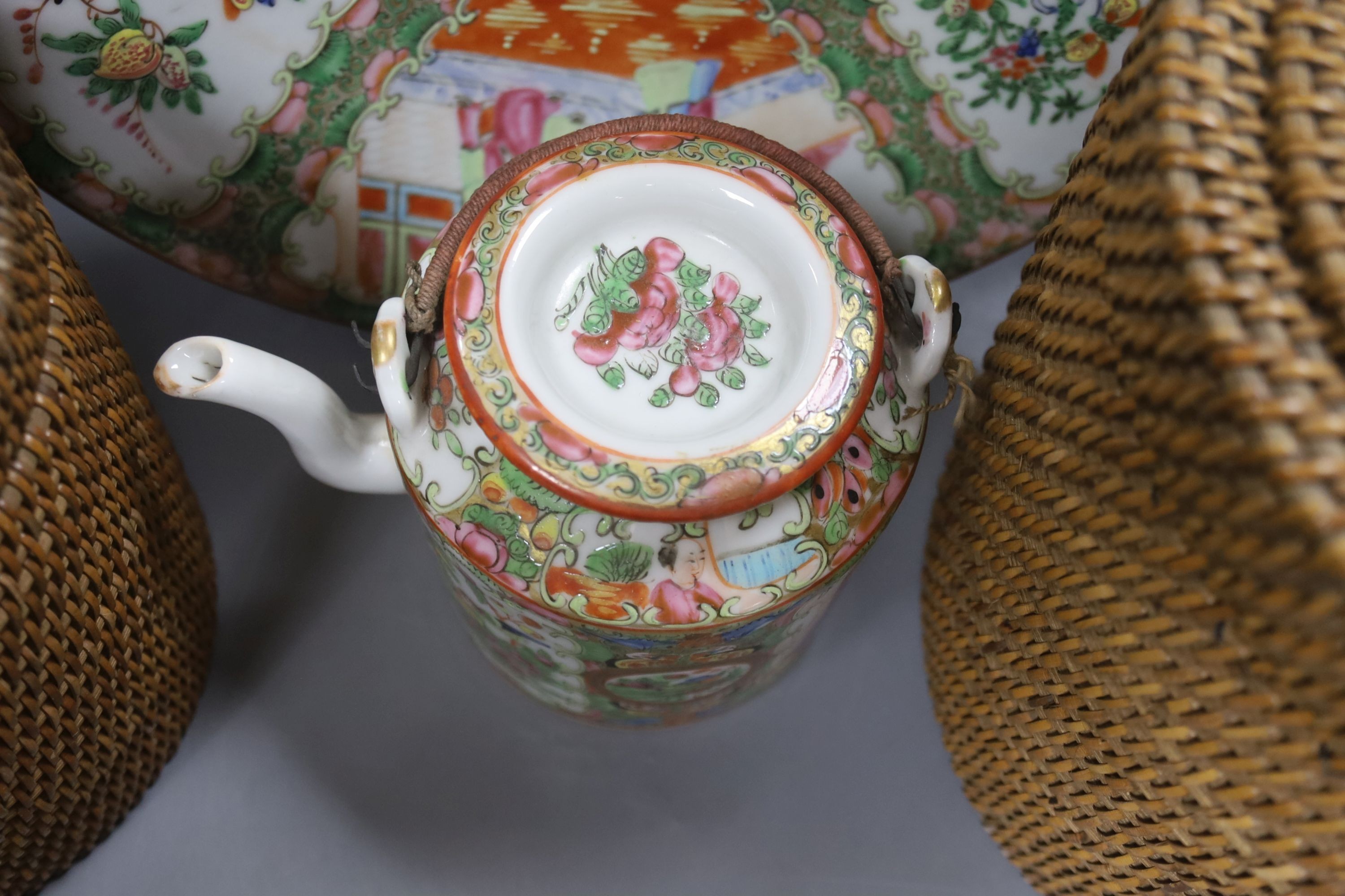 Three late 19th/early 20th century Chinese famille teapots, two in baskets and a similar dish, dish 29.5 cms diameter.